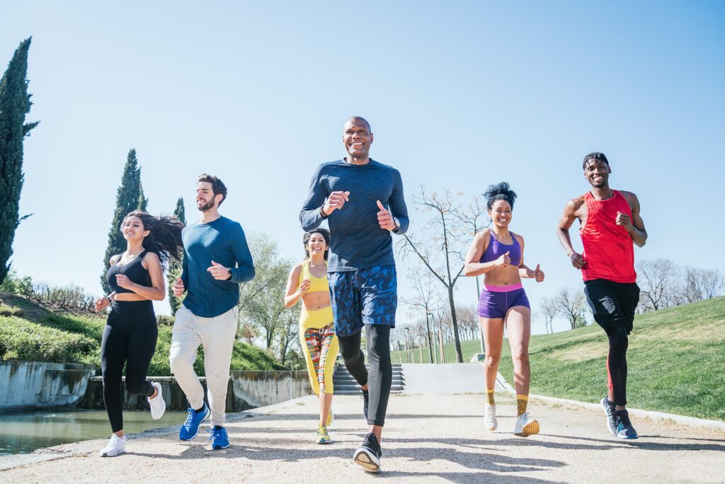 Group of diverse runners training in a park, emphasizing active lifestyles and foot health, relevant to athlete's foot prevention and treatment.
