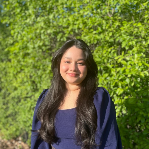 Shawana, office manager at Opensky Podiatry, smiling outdoors with green foliage in the background.